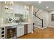 Elegant wet bar with mirrored backsplash, wine fridge, and custom cabinetry next to staircase at 2156 Cheswick Ln, Mount Pleasant, SC 29466