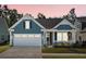 A charming home at dusk featuring a two-car garage, inviting porch, and manicured lawn at 222 River Martin Ct, Summerville, SC 29483