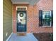 Close-up of the front door features a wreath and a 'hello' mat, framed by brick and siding at 225 Nelliefield Creek Dr, Wando, SC 29492
