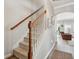 Carpeted staircase with white risers and wooden handrail leading to the upper level of the home at 225 Nelliefield Creek Dr, Wando, SC 29492