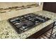 Close-up of a gas cooktop with granite countertops and decorative tile backsplash at 402 Spectrum Rd, Summerville, SC 29486
