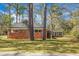 View of backyard showing exterior brick, mature trees, and healthy grass lawn at 407 Hayne St, Walterboro, SC 29488