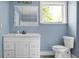 Bathroom with a white vanity, toilet, framed mirror, and a window providing natural light at 407 Hayne St, Walterboro, SC 29488