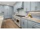 Gourmet kitchen with a white range, hood vent, marble backsplash, and stylish blue cabinetry at 499 Lackland Ct, Mount Pleasant, SC 29464