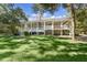 Stunning raised home featuring a spacious porch, grand columns, and lush landscaping at 5991 Joseph Blake Ln, Wadmalaw Island, SC 29487