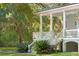 Charming porch with white columns and stairs, surrounded by lush greenery and landscaping at 5991 Joseph Blake Ln, Wadmalaw Island, SC 29487