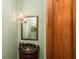 Elegant powder room with a decorative mirror, unique light fixture, and dark granite countertop at 5991 Joseph Blake Ln, Wadmalaw Island, SC 29487
