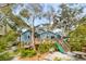 Charming backyard with a blue home, deck, mature trees, wooden walkways, and a slide at 619 E Erie Ave, Folly Beach, SC 29439
