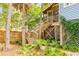 Charming backyard with lush greenery and a wooden staircase leading to the house at 619 E Erie Ave, Folly Beach, SC 29439