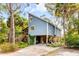 Coastal home with a modern design, raised elevation, and a spacious driveway surrounded by lush greenery at 619 E Erie Ave, Folly Beach, SC 29439