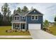 Two-story home with blue siding, covered porch, two-car garage, and well-manicured lawn at 641 Cottage Landing Dr, Summerville, SC 29485