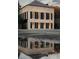 A close exterior view of a cream-colored two-story building with striking black shutters and a reflection in a puddle at 90 E Bay St, Charleston, SC 29401