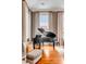 Close up of the living area with grand piano, a comfortable chair, and large bright windows with luxurious curtains at 90 E Bay St, Charleston, SC 29401