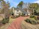 Inviting yellow home with a spacious front yard, mature trees, and a long red driveway leading to the property at 941 Law Ln, Mount Pleasant, SC 29464
