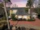 Charming yellow home with well-manicured landscaping, featuring a unique fountain and a red paved driveway at 941 Law Ln, Mount Pleasant, SC 29464