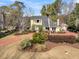 Beautiful yellow house boasting lush landscaping, a decorative fountain, and a vibrant red driveway at 941 Law Ln, Mount Pleasant, SC 29464