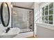 Bright bathroom features a tiled shower with glass door, modern vanity and fixtures, and a large window at 100 Queen St, Charleston, SC 29401