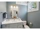 Bathroom featuring a gray vanity with marble countertop, brass fixtures, and framed oval mirror at 100 Queen St, Charleston, SC 29401