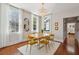 A dining room with gold chairs, an elegant chandelier, and natural light from two large windows at 100 Queen St, Charleston, SC 29401