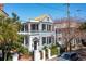 Charming two-story home with a beautiful balcony, black shutters, and mature landscaping at 100 Queen St, Charleston, SC 29401
