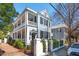 Charming two-story home with a double porch, black shutters, and a brick-lined walkway at 100 Queen St, Charleston, SC 29401