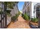 Brick pathway between two homes leading to a secluded entrance, enhanced with mature shrubs at 100 Queen St, Charleston, SC 29401