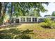 Backyard view showing white trim windows of sunroom, brick exterior and grassy yard with mature trees at 108 Nightingale Manor, North Charleston, SC 29418