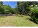 A grassy lawn with a tall privacy fence along the side and thick mature trees and shrubs at 108 Nightingale Manor, North Charleston, SC 29418