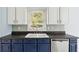 Bright kitchen with white and blue cabinets, stainless steel appliances and sink under a window at 1491 Seacroft Rd, James Island, SC 29412