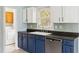 Well lit kitchen with stainless steel dishwasher, blue lower cabinets and washer and dryer located just behind the sink at 1491 Seacroft Rd, James Island, SC 29412