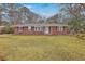 Charming brick home with a manicured front lawn, complemented by mature trees and classic black shutters at 2410 Trent St, Charleston, SC 29414