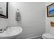 A well-lit powder room featuring a pedestal sink, toilet, and shiplap walls with decorative art at 2514 Myrtle Ave, Sullivans Island, SC 29482