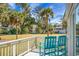 Balcony view with teal chairs overlooking a large grassy lawn with palm trees and other mature trees at 278 Driftwood Ln, Edisto Island, SC 29438