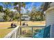 Charming outdoor balcony with blue chairs overlooking golf carts on manicured grass with palm trees at 278 Driftwood Ln, Edisto Island, SC 29438