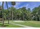 Scenic golf course view with lush green grass, sand trap, and tall trees under a partly cloudy sky at 278 Driftwood Ln, Edisto Island, SC 29438