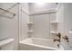 All-white bathroom with tub-shower combo featuring toiletry shelves and bronze fixtures at 3092 Emma Ln, Mount Pleasant, SC 29466