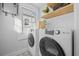 Well-lit laundry area featuring modern washer and dryer, and wooden shelves with decor at 42 Kennedy St, Charleston, SC 29403