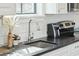 Close-up of a kitchen sink with black countertops, white cabinets, and stainless steel faucet and modern finishes at 425 Mccants Dr, Mount Pleasant, SC 29464