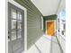 Inviting front porch with white railing, green siding, and access to a side yard with lush green trees at 5 Maranda Holmes St, Charleston, SC 29403