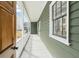 Inviting front porch with white railing, green siding, and natural light streaming through windows at 5 Maranda Holmes St, Charleston, SC 29403