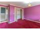 Bedroom with pink walls, red carpet, and a closet with bi-fold doors, ready for renovation at 609 Levee Dr, Moncks Corner, SC 29461