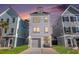 Charming three-story home with a one car garage and a well-manicured lawn at dusk at 1002 Carmela Ct, North Charleston, SC 29405