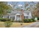 Inviting home with a well-manicured lawn, brick chimney, and charming front porch at 105 S Palmetto St, Summerville, SC 29483