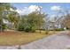 Scenic view of a home surrounded by lush greenery and tall trees and a paved driveway at 105 S Palmetto St, Summerville, SC 29483