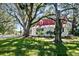 Charming home with red roof nestled among mature trees and a green lawn, creating a picturesque setting at 127 Oak St, McClellanville, SC 29458