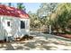 Quaint home with red roof and white siding, complemented by lush greenery and a secure gate at 127 Oak St, McClellanville, SC 29458