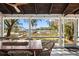 Inviting screened porch with views of the water and dock featuring a rustic wood dining table and wood-paneled ceiling at 127 Oak St, McClellanville, SC 29458