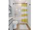 Well-lit bathroom featuring a white tiled shower and a yellow striped shower curtain, along with wood-look floors at 142 Midtown Ave, Summerville, SC 29486