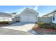 Two-car garage and paved driveway with landscaping and grey privacy fence at 142 Midtown Ave, Summerville, SC 29486