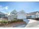A two-car garage exterior with shrubbery, landscaping, and a paved driveway at 142 Midtown Ave, Summerville, SC 29486